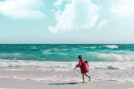 Happy little girl playing on beach photo