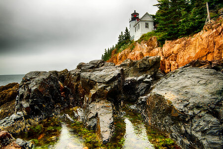 Lighthouse on the rocks on shoreline landscape photo
