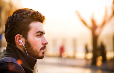 Young Man with In-ear Headphones Portrait in Profile Outdoors photo
