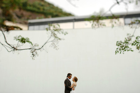 Bride and Groom Standing at a High White Wall photo
