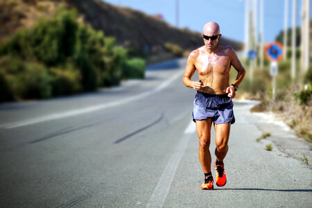 Bald Tanned Man with Sunglasses Jogging During a Hot Day photo