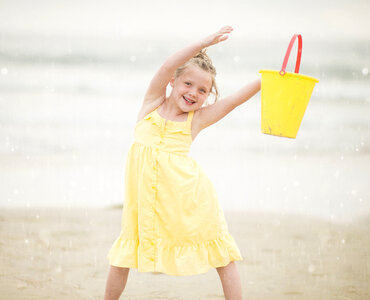 Girl in Yellow Dress Having Fun Playing on a Beach with Bucket photo