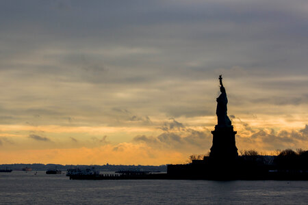 Silhouette of the Statue of Liberty Viewed from Distance at Sunset photo