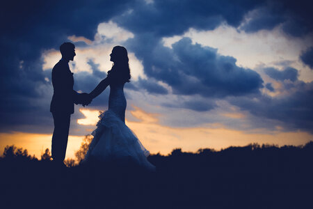 Wedding Couple on the Hill Holding Hands at Sunset photo