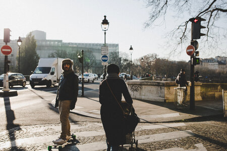 Lady with a Stroller and a Skateboarder Crossing the Street photo