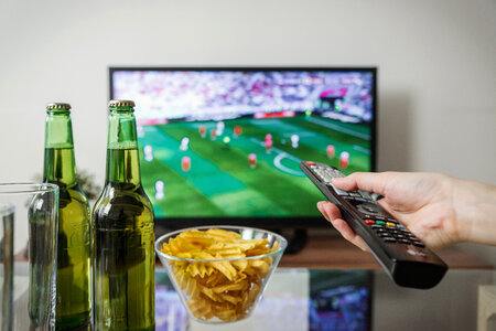1 Watching football match on tv with remote controller. photo