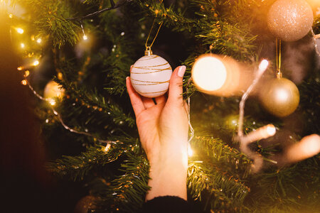 Woman in sweater decorating Christmas tree with baubles photo