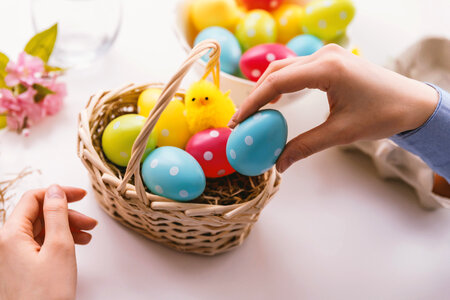 Happy Easter! Young woman is giving painted eggs to basket photo