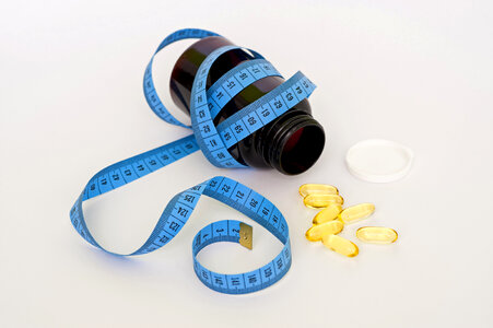 Yellow Pills coming out of bottle with measuring tape photo