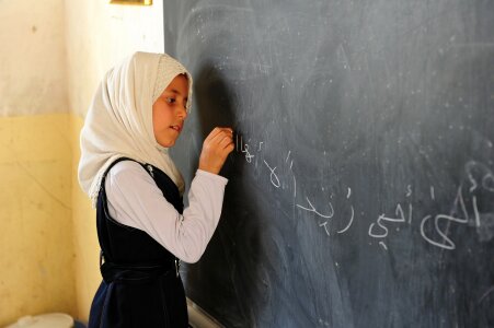 Girl writing math equations on a blackboard in class