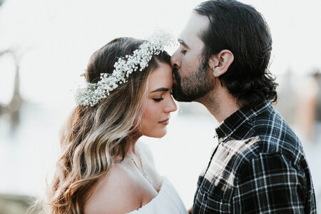 Beard Man Kisses in Forehead Beautiful Woman with Floral Wreath photo