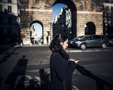 Brunette Walking the Street with a Smartphone in her Hands photo