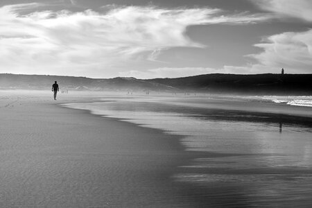 A young man walk on a black sand beach photo