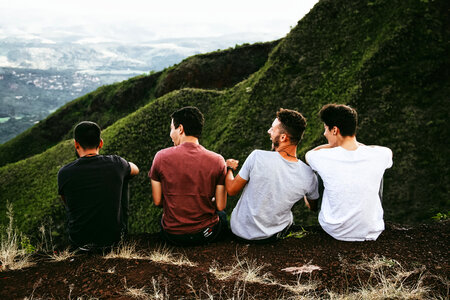 Four Guys Sitting on Cliff and Talking and Laughing photo
