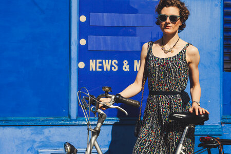 A Woman standing in Front of the Blue, Vintage Wall, Holding a City Bicycle photo