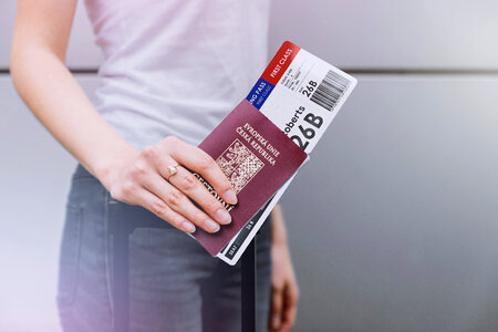 Woman waiting at an airport, holding ticket with passport