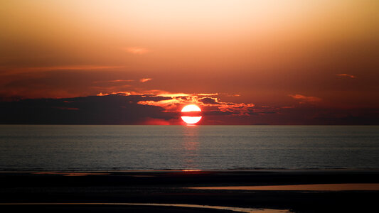 right sun in an orange sky with dark clouds at sunset photo