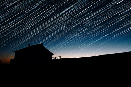 Star Trails and house silhouette at night astrophotography photo