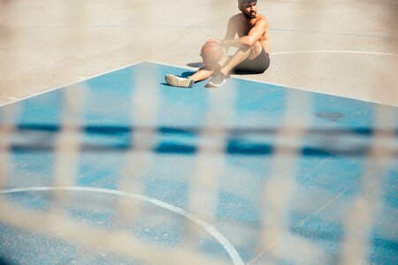 Man Sitting On Basketball Court photo