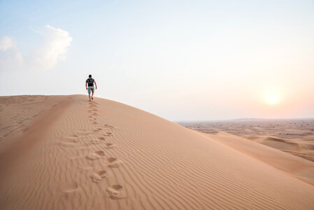 Man Walking Up Sand Dunes photo