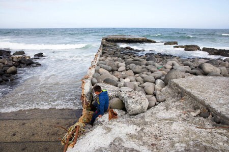 Child sits on the remains of the East Landing boat launch