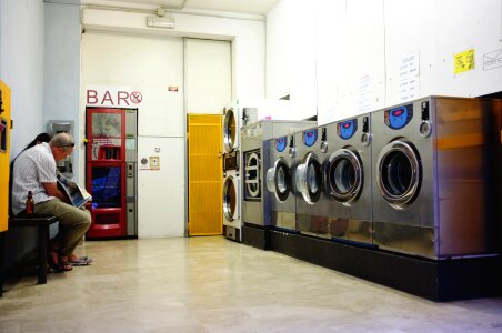 A row of industrial washing machines in a public laundromat photo