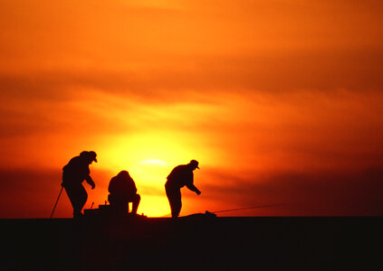 silhouette of fisherman by the ocean in sunrise photo