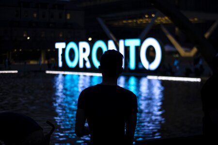 Toronto sign in Nathan Phillips Square lit in purple, white and photo