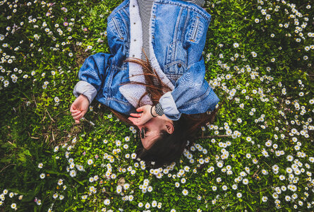 Young Brunette Enjoying Lying on the Grass full of Daisies