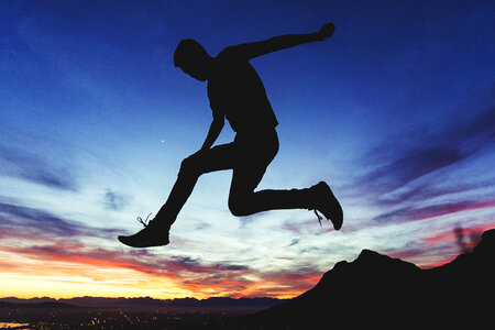 Silhouette of a Man Jumping at the Sunset photo