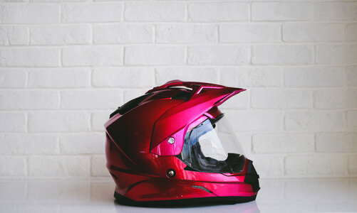 Red Metallic Motorcycle Helmet against White Brick Wall photo