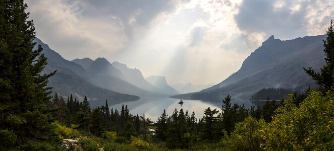 Sunlight from above the clouds over the lake at Glacier National Park, Montana photo