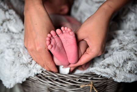 Mother Hands Holding Feet of Newborn Baby photo
