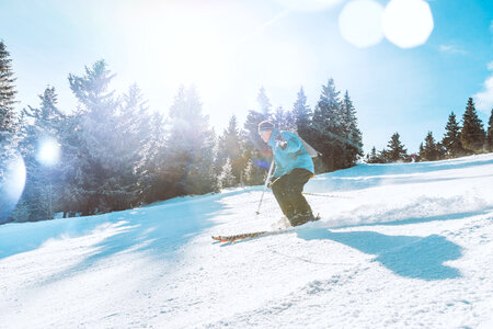 Skier skiing downhill during sunny day in high mountains photo