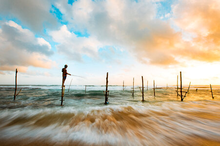 Time-Lapse landscape with fisherman under clouds and sky in Hikkaduwa, Sri Lanka photo