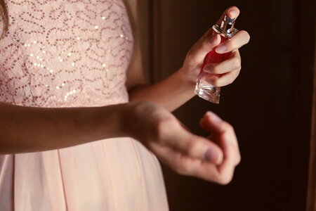 Beautiful young woman with bottle of perfume at home, closeup photo