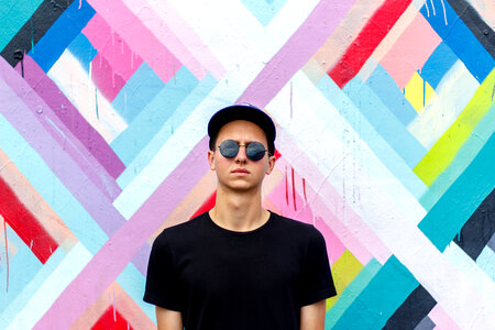 Serious Young Man Wearing Black T-Shirt Standing against Colorful Wall photo