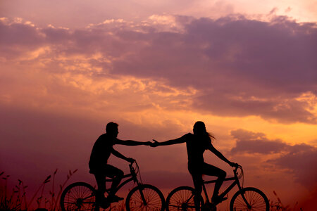Couple Stretching Arms to each other While Riding Bicycles photo