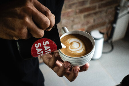 Barista making a perfect latte art on flatwhite photo