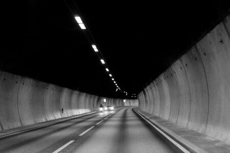 Black and white image of a man riding a scooter into a tunnel photo