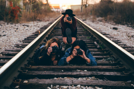 Three Young Girls Taking Pictures on Railroad Tracks photo