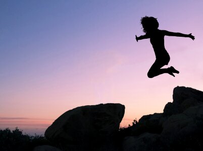 Girl leaping off rock silhouette jump photo