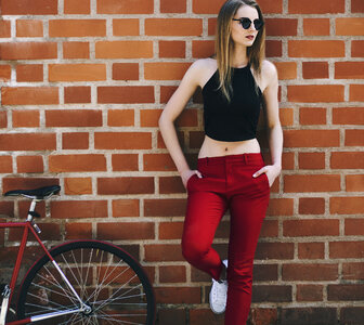 Young Woman with Her Bike Leaning against Red Brick Wall photo