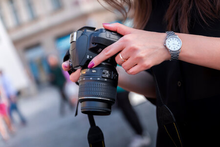 Young photographer checks the her DSLR camera in the city center photo