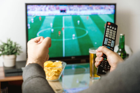 2 Watching football match on tv with remote controller. photo
