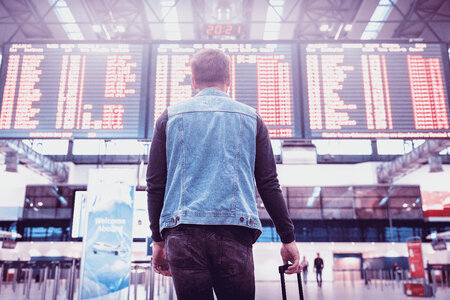 Young man with luggage checking flight timetable in international airport photo