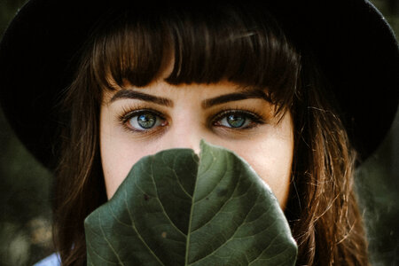 Lovely Brunette Covers Her Mouth behind the Leaf photo