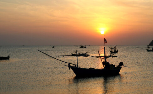 Boats in the ocean at sunset in Thailand photo
