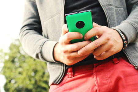 Boy holding a green smartphone in the hands photo