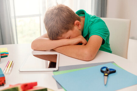 Schoolboy crying or sleeping at his desk at home photo